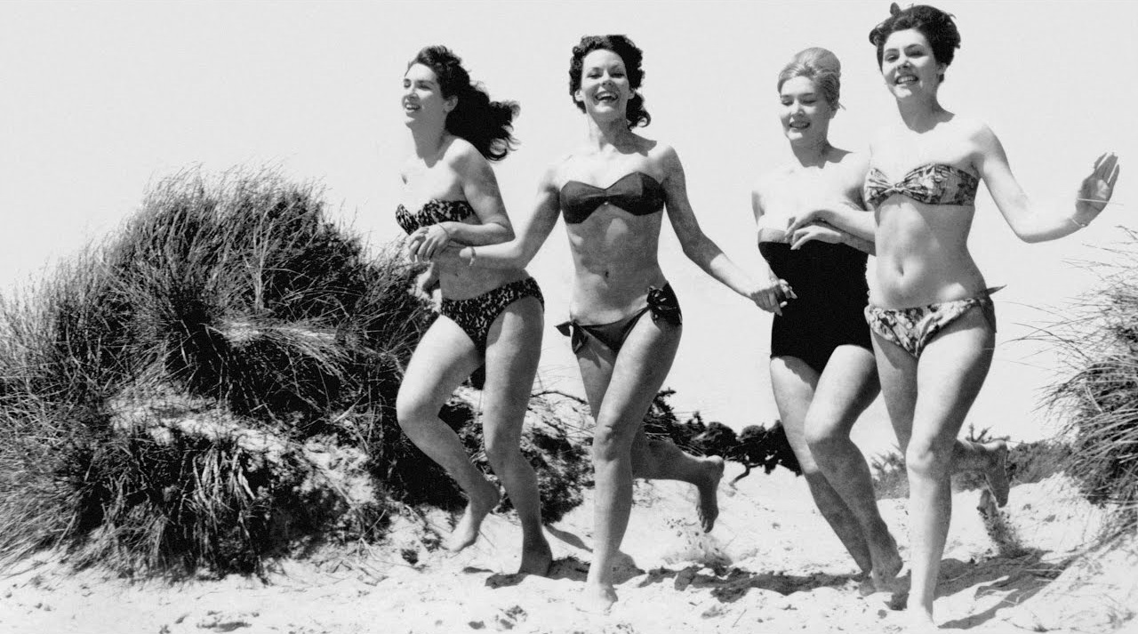 Old photo of women running on beach in bikini