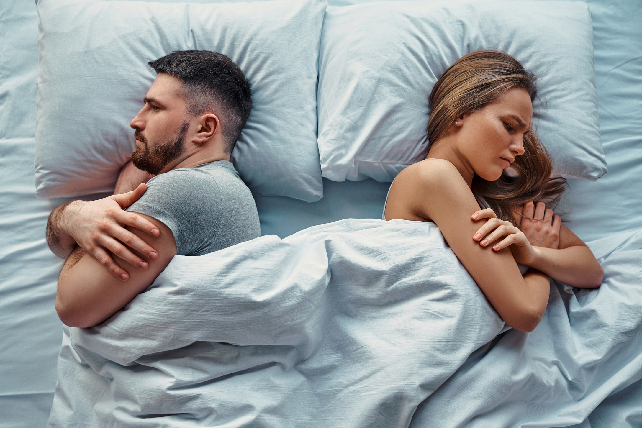Man and woman in bed with their backs to eachother