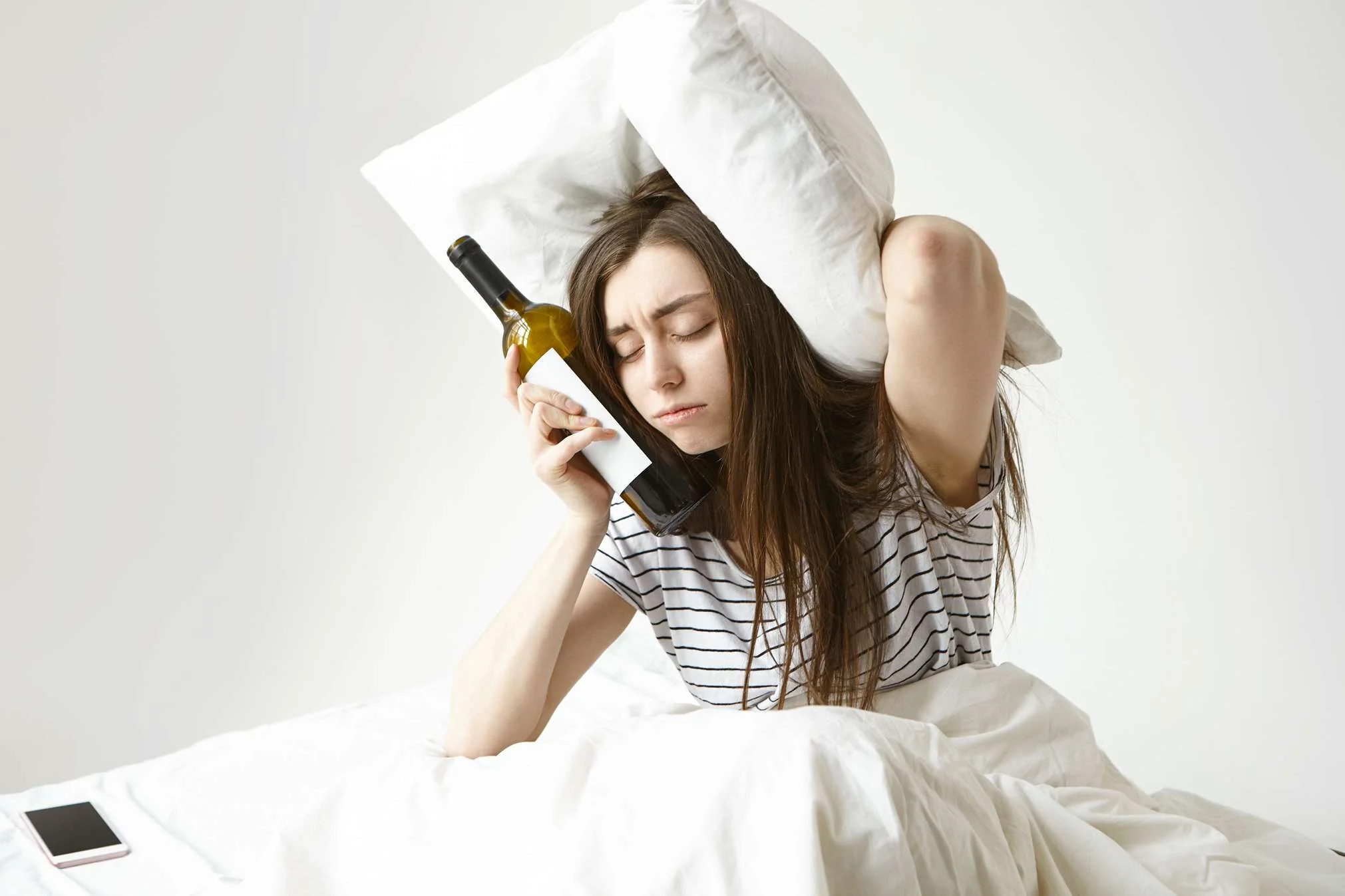 Woman with a bottle of wine in bed