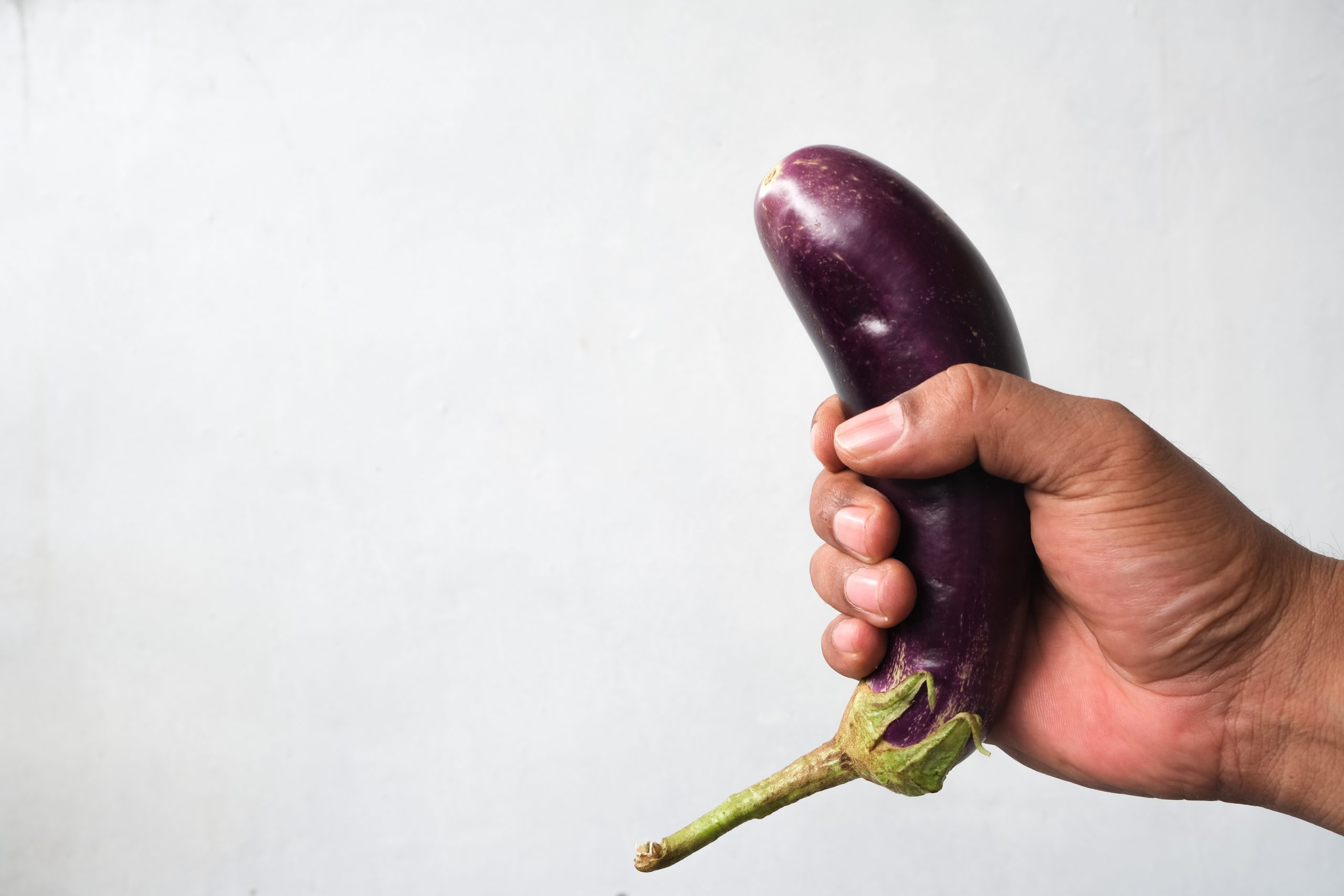 Man met een aubergine in zijn hand