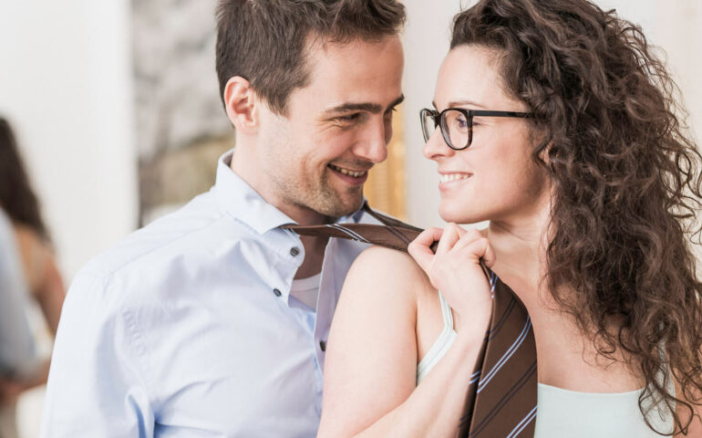 Woman pulls man's tie and laughs