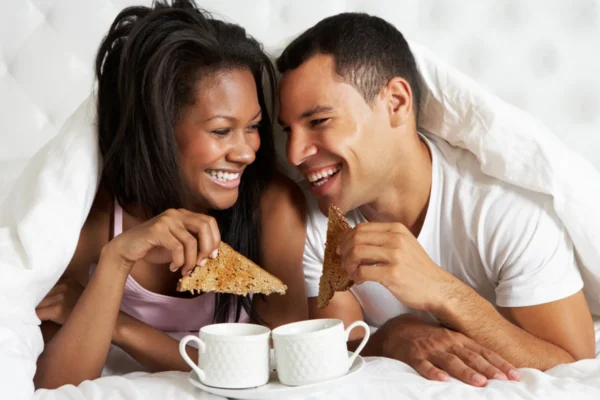 Man and woman enjoying breakfast in bed