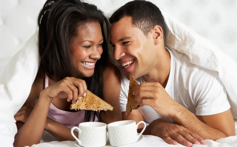 Man and woman enjoying breakfast in bed