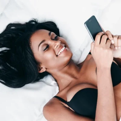 Sexy vrouw op bed met haar telefoon