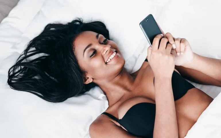 Sexy vrouw op bed met haar telefoon