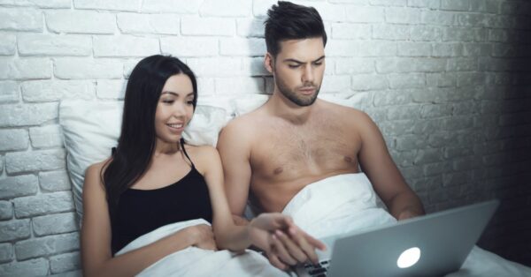 Man and woman looking at a laptop in bed