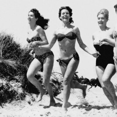 Old photo of women running on beach in bikini