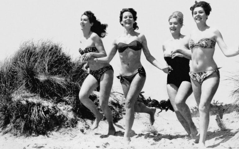 Oude foto van vrouwen die in bikini over het strand rennen