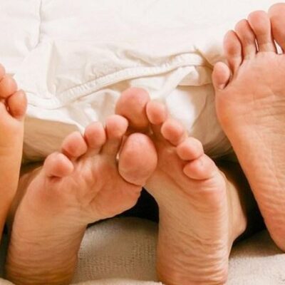 Three pair of feet in bed