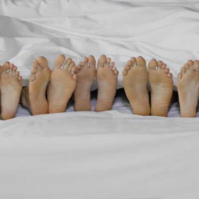 5 pair of feet in a bed